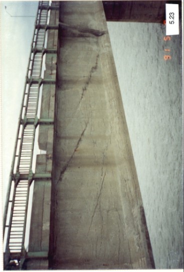 État d'une poutre de rive présentant des fissures qui suivent le tracé des gaines de post-tension internes et montrant la barrière d’origine et les drains du tablier le long de sa bordure. Rapport d’inspection annuelle de 1991